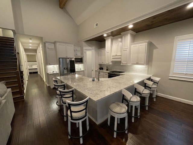 kitchen featuring stainless steel appliances, a breakfast bar area, white cabinets, and beam ceiling