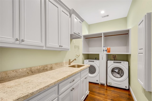 washroom with cabinets, dark hardwood / wood-style floors, washer and clothes dryer, and sink