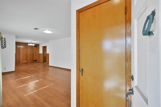 interior space featuring wood-type flooring, a chandelier, and wood walls