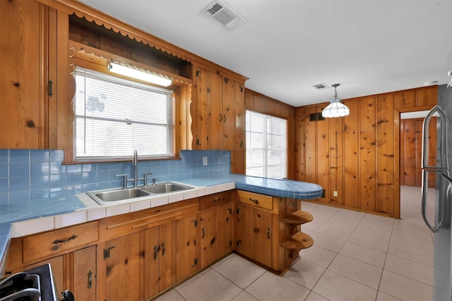 kitchen with refrigerator, tile countertops, decorative light fixtures, and sink