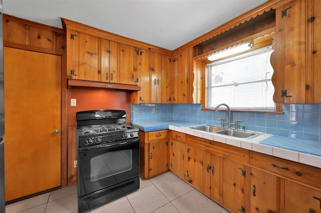 kitchen featuring light tile patterned flooring, sink, tile counters, and black range with gas cooktop