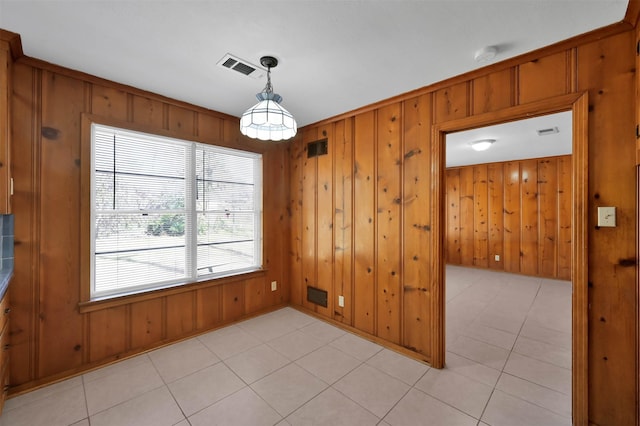 unfurnished dining area with light tile patterned floors and wooden walls