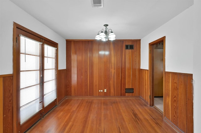 unfurnished dining area featuring hardwood / wood-style flooring and a chandelier