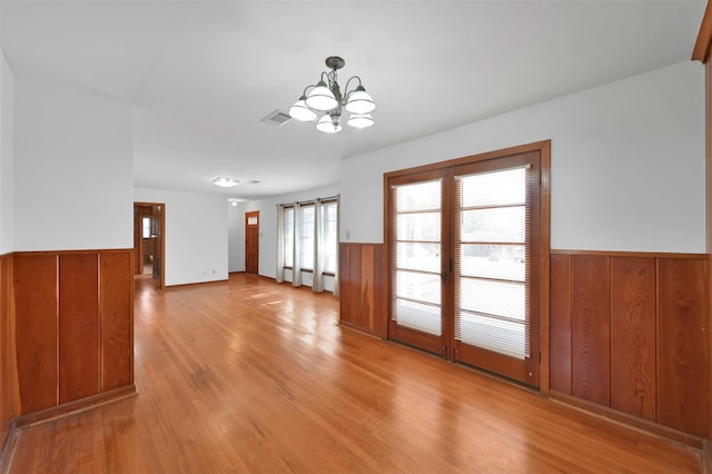 unfurnished room with a chandelier and light hardwood / wood-style flooring