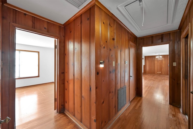 hallway with light wood-type flooring and wooden walls