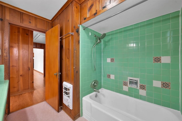 bathroom with heating unit, tiled shower / bath combo, and wooden walls