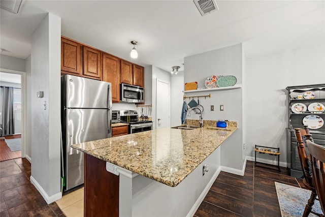 kitchen with hardwood / wood-style floors, sink, light stone counters, kitchen peninsula, and stainless steel appliances