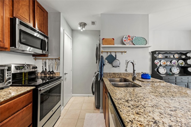 kitchen featuring appliances with stainless steel finishes, sink, light tile patterned floors, and light stone counters