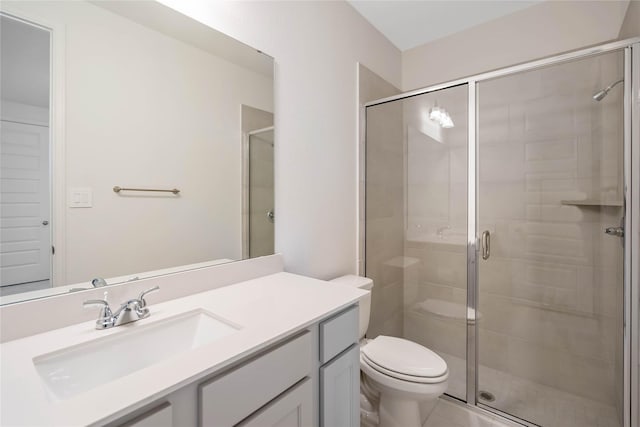 bathroom featuring vanity, a shower with door, and toilet