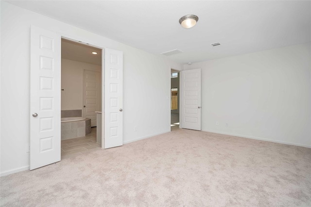 unfurnished bedroom featuring connected bathroom and light carpet