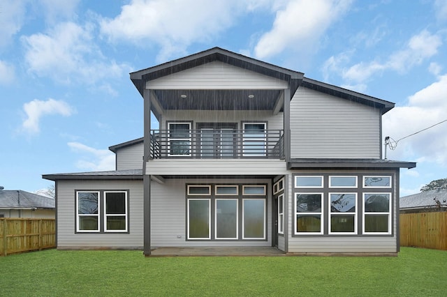 back of house with a balcony and a yard