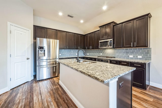 kitchen with dark wood-type flooring, lofted ceiling, sink, a center island with sink, and stainless steel appliances