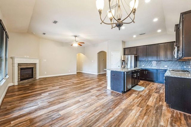 kitchen with pendant lighting, an island with sink, decorative backsplash, stainless steel appliances, and dark brown cabinets