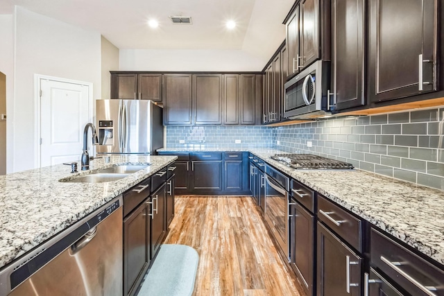 kitchen featuring light stone counters, appliances with stainless steel finishes, sink, and light hardwood / wood-style flooring