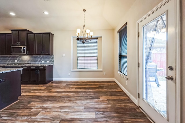 kitchen with lofted ceiling, dark brown cabinets, dark hardwood / wood-style floors, a notable chandelier, and backsplash