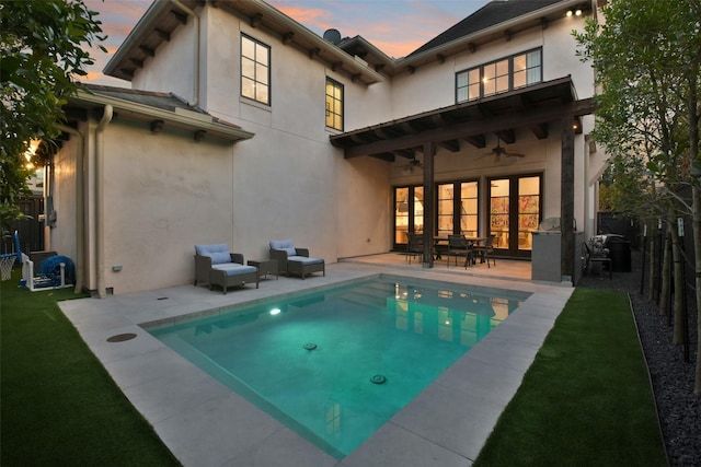 back house at dusk with ceiling fan and a patio area