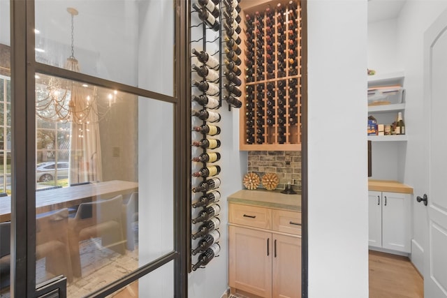 wine room featuring light hardwood / wood-style flooring and a notable chandelier