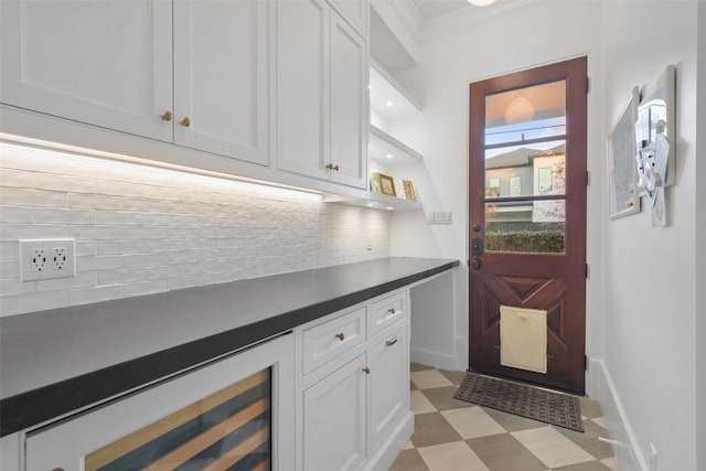 kitchen with decorative backsplash, ornamental molding, and white cabinets