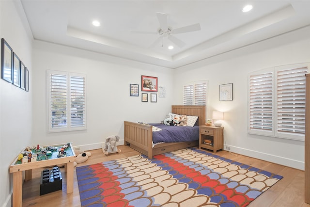 bedroom featuring hardwood / wood-style floors, a tray ceiling, and ceiling fan