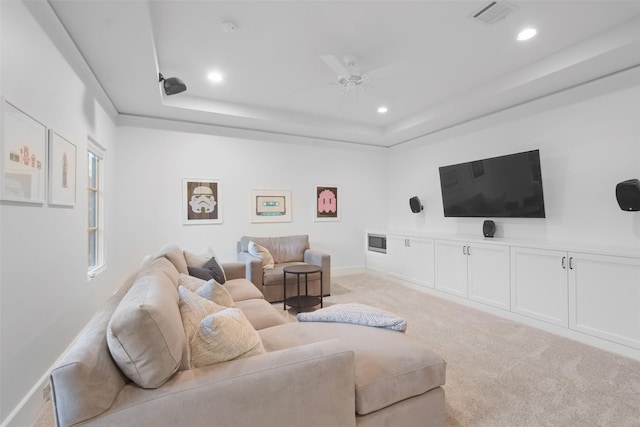 carpeted living room featuring a raised ceiling and ceiling fan