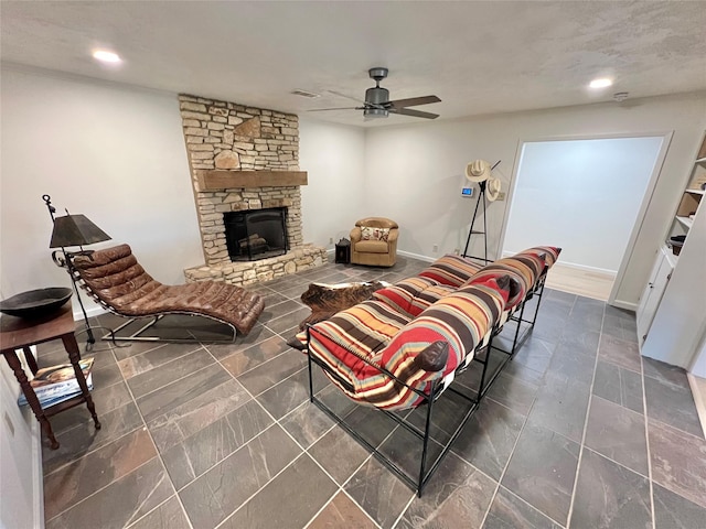 living room with ceiling fan and a stone fireplace