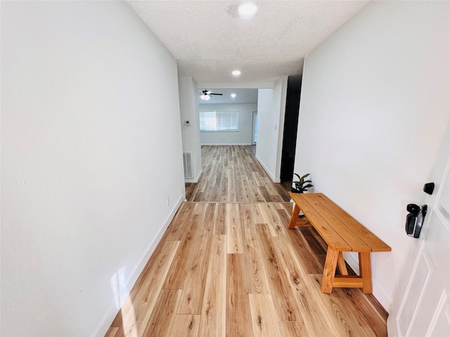 hall with light hardwood / wood-style floors and a textured ceiling