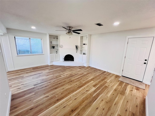 unfurnished living room with ceiling fan, built in features, light hardwood / wood-style flooring, and a textured ceiling