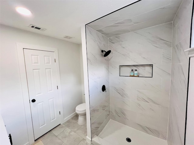 bathroom with a tile shower and toilet