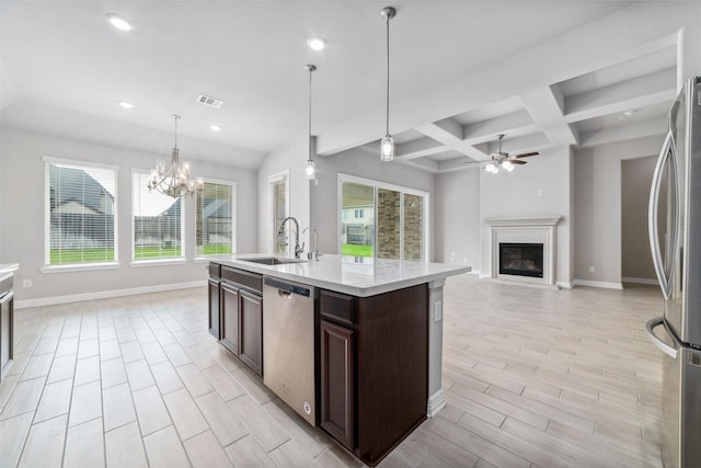 kitchen featuring dark brown cabinetry, sink, pendant lighting, stainless steel appliances, and a kitchen island with sink