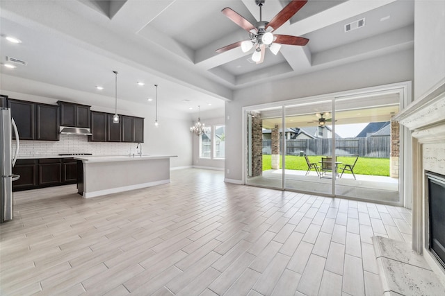 unfurnished living room with coffered ceiling, a premium fireplace, sink, and ceiling fan with notable chandelier