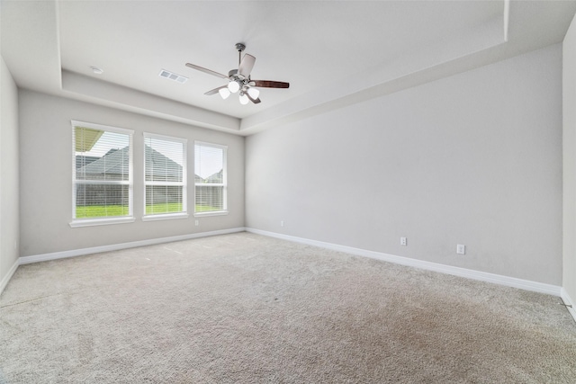 carpeted spare room with ceiling fan and a tray ceiling