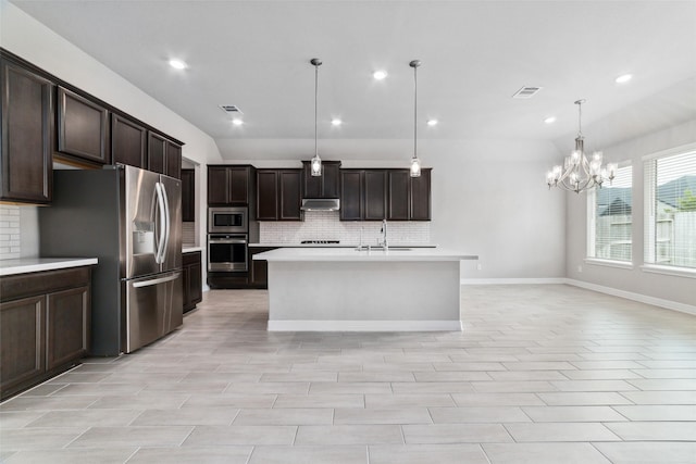 kitchen featuring pendant lighting, stainless steel appliances, tasteful backsplash, dark brown cabinetry, and a center island with sink