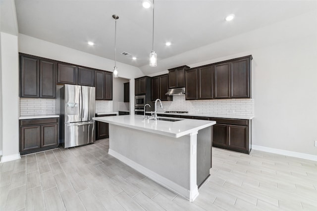 kitchen featuring hanging light fixtures, backsplash, stainless steel appliances, and an island with sink