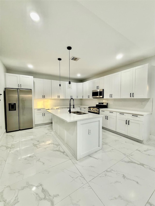 kitchen featuring an island with sink, sink, white cabinets, hanging light fixtures, and stainless steel appliances