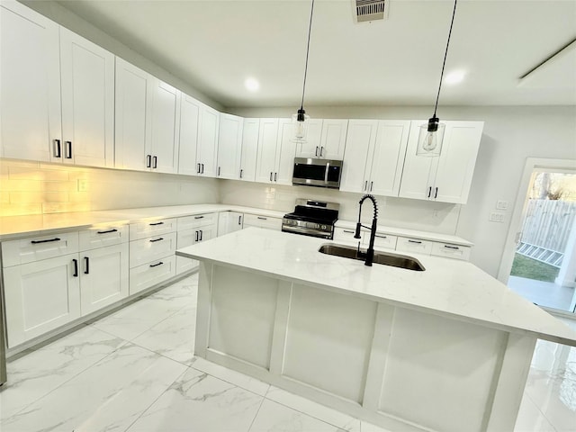 kitchen featuring sink, white cabinetry, stainless steel appliances, light stone countertops, and decorative light fixtures