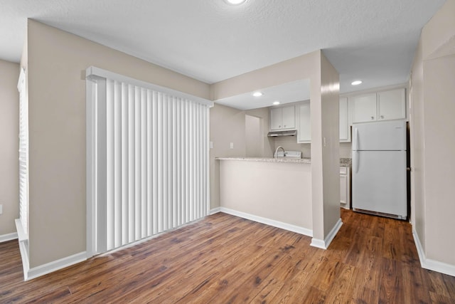 kitchen featuring a textured ceiling, dark hardwood / wood-style flooring, white fridge, light stone countertops, and white cabinets