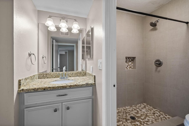 bathroom featuring vanity, toilet, and tiled shower