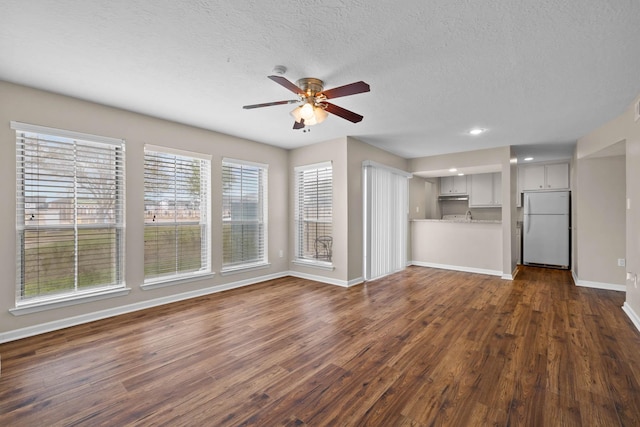 unfurnished living room featuring dark hardwood / wood-style flooring, a textured ceiling, and ceiling fan