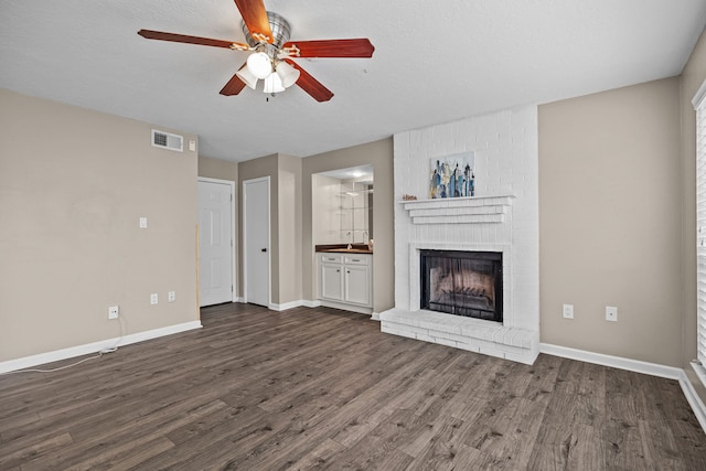 250 El Dorado Blvd Unit 127, Webster, TX 77598 - unfurnished living room with ceiling fan, dark wood-style floors, a fireplace, baseboards, and a sink