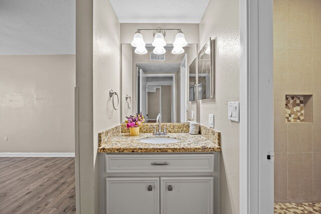 250 El Dorado Blvd Unit 127, Webster, TX 77598 - bathroom with a chandelier, vanity, wood finished floors, a textured wall, and baseboards