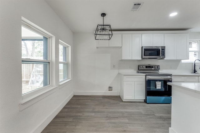 kitchen with tasteful backsplash, decorative light fixtures, stainless steel appliances, light hardwood / wood-style floors, and white cabinets