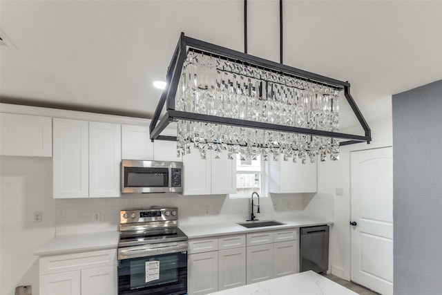 kitchen featuring appliances with stainless steel finishes, sink, decorative backsplash, and white cabinets