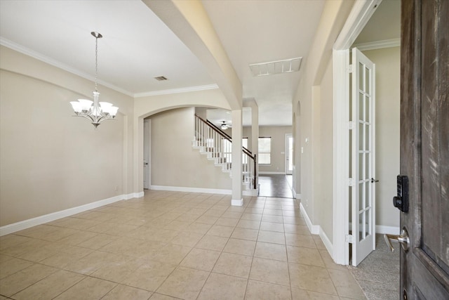 tiled foyer featuring crown molding and a chandelier