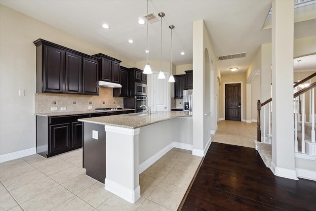 kitchen with light stone countertops, light tile patterned flooring, appliances with stainless steel finishes, and pendant lighting