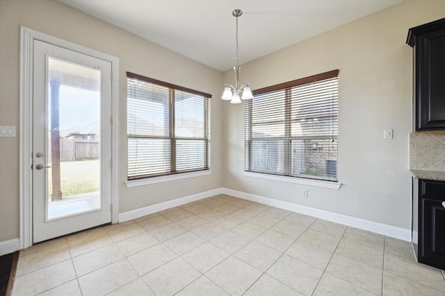 unfurnished dining area with a healthy amount of sunlight, light tile patterned floors, and an inviting chandelier