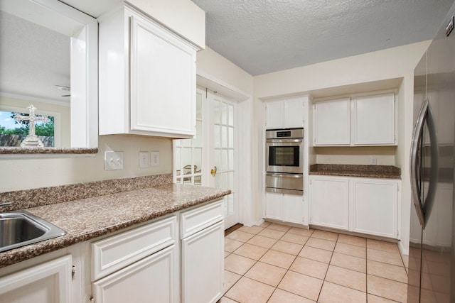 kitchen featuring white cabinetry, light tile patterned floors, a textured ceiling, and appliances with stainless steel finishes