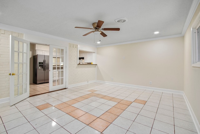 spare room featuring light tile patterned floors, ceiling fan, ornamental molding, brick wall, and french doors