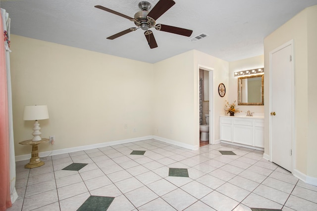 interior space with ceiling fan, sink, light tile patterned floors, and ensuite bath