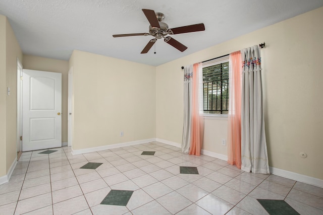 spare room with light tile patterned flooring, ceiling fan, and a textured ceiling