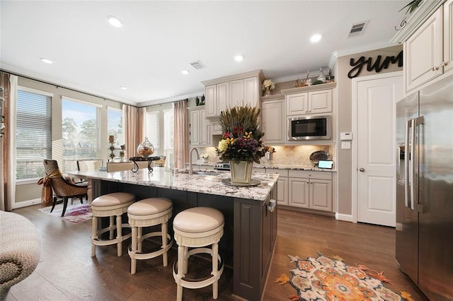 kitchen with sink, dark hardwood / wood-style flooring, a kitchen island with sink, stainless steel appliances, and crown molding